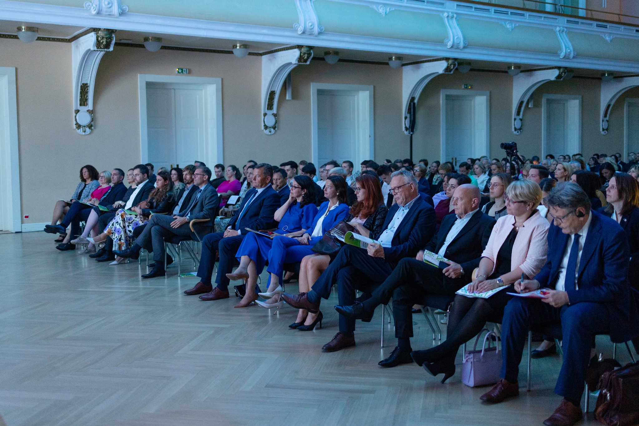 Udeleženci slovesnosti ob zaključku izvajanja evropske kohezijske politike 2014-2020 v Sloveniji. V prvi vrsti sedijo visoki predstavniki Evropske komisije, ministri in državni sekretarji.