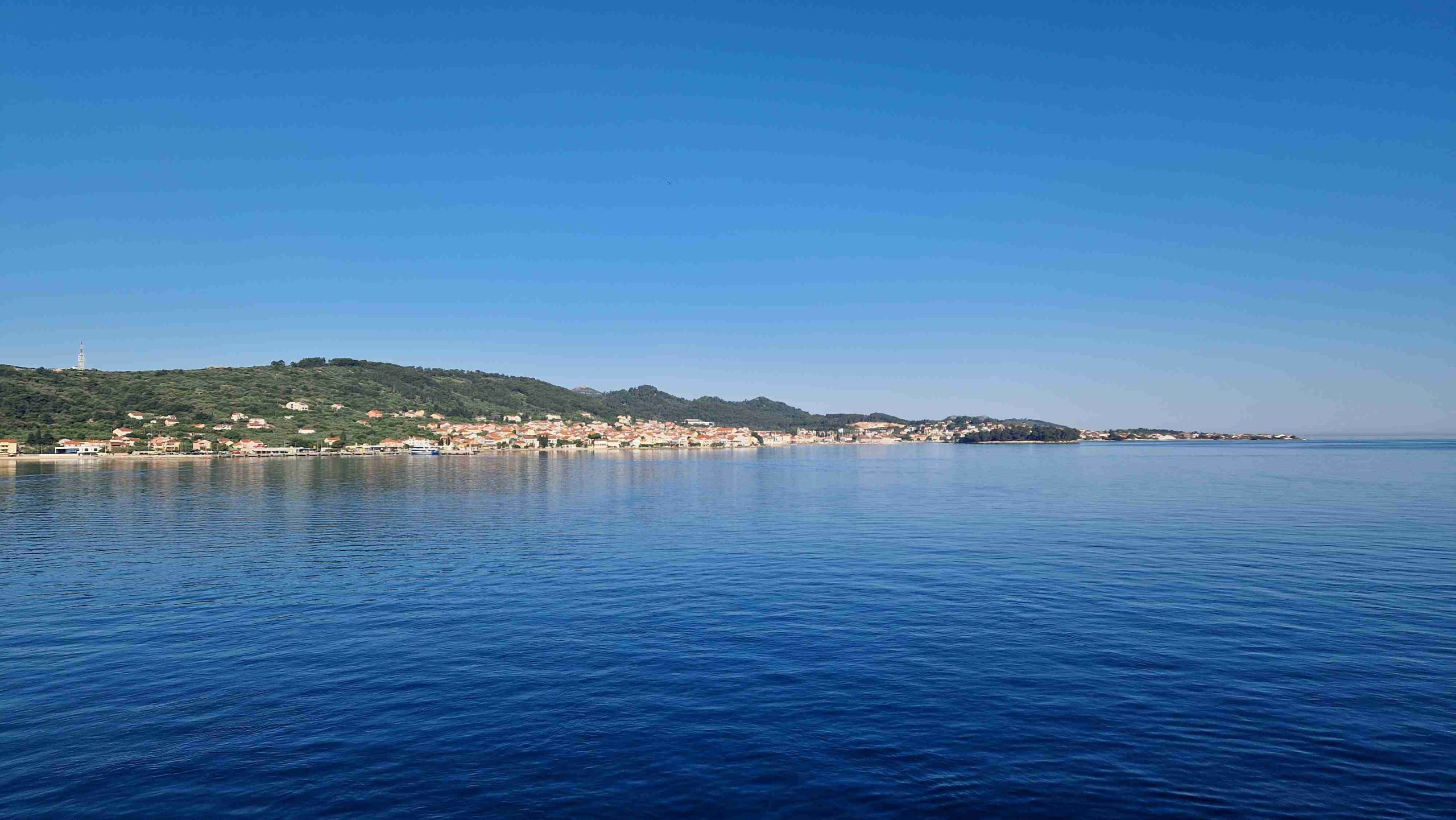 V ospredju morej, v ozadju obala z manjšim krajem pod vzpetino.