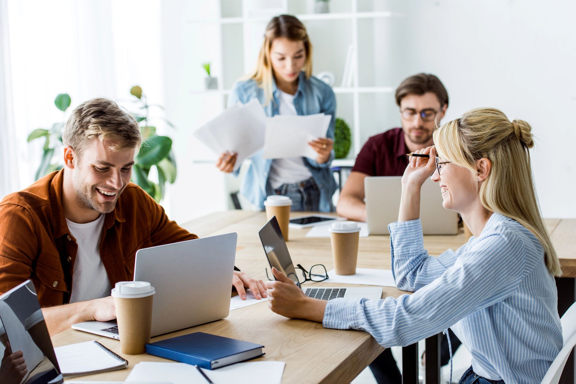Štirje mladi podjetniki med sestankom sedijo ob mizi