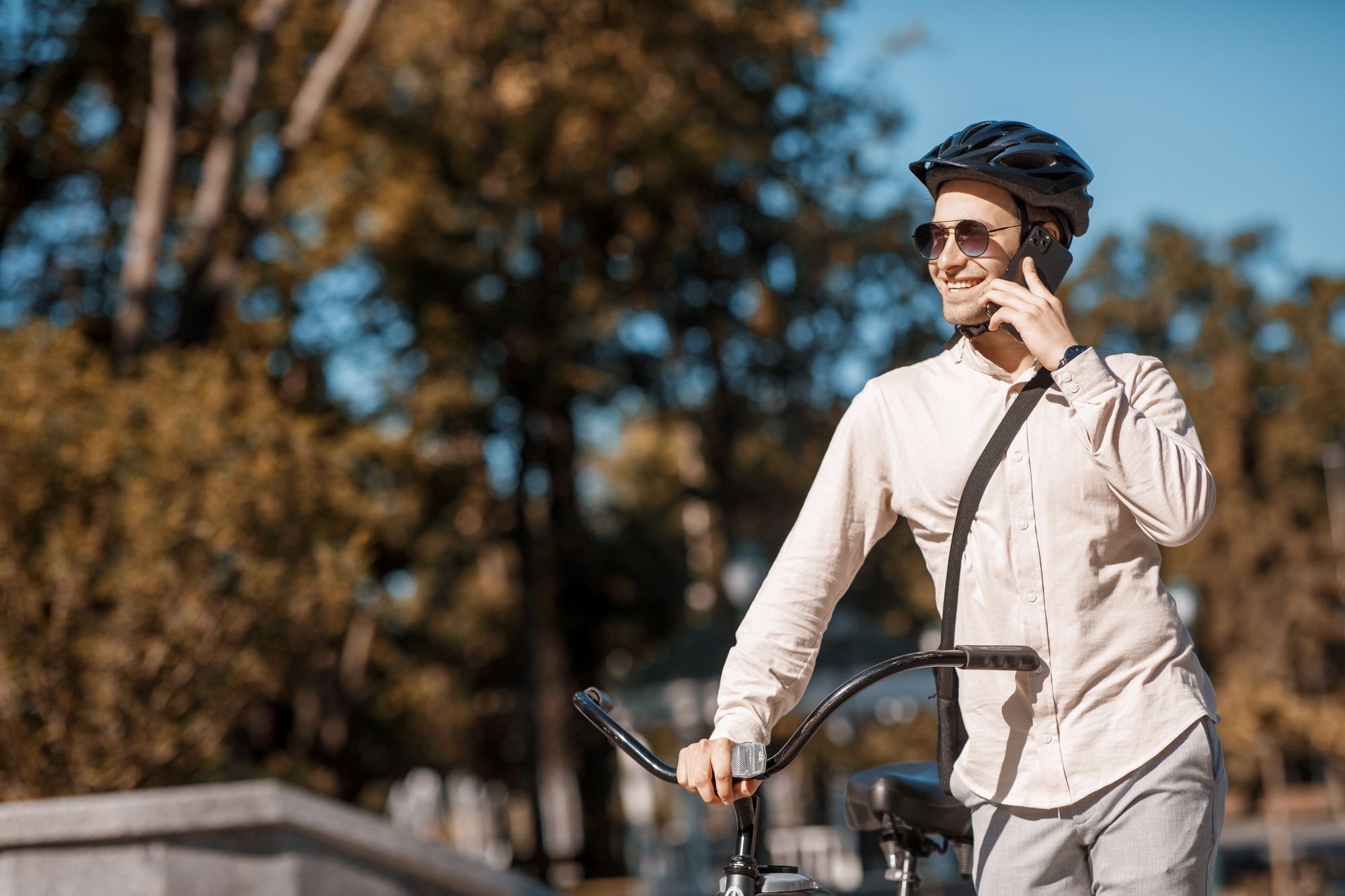 Mlad moški stoji ob kolesu in govori po telefonu.