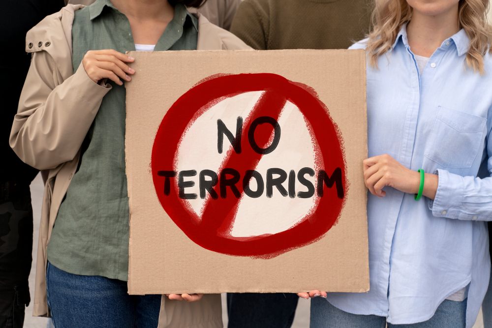 ljudje nosijo transparent proti terorizmu