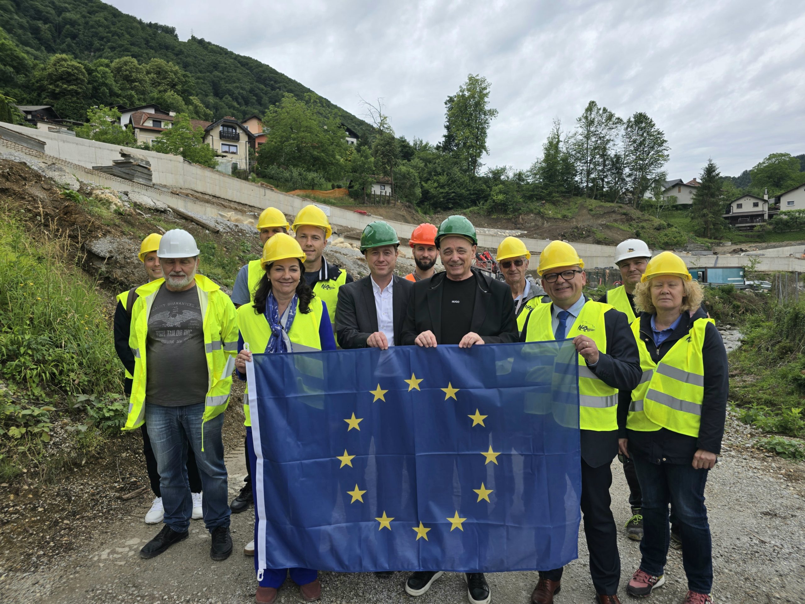 Udeleženci ogleda gradbišča plaz z razvito evropsko zastavo